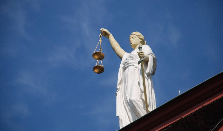 Lady Justice holding the scales on top of a court house