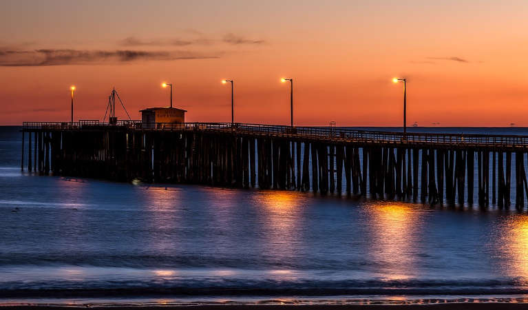 Sunset in California, with the wharf poorly lit in the dusk.