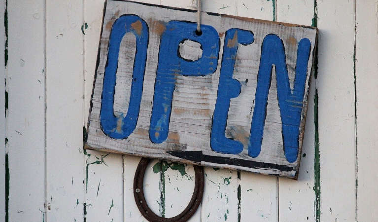A sign saying open on a wooden door.