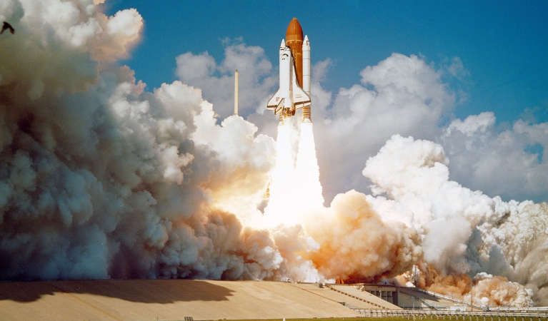 The Challenger space shuttle launching off its pad.
